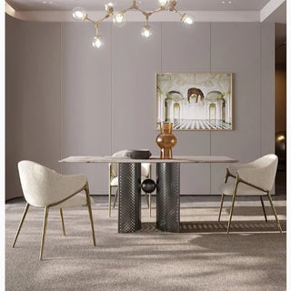Two cream dining chairs with gold legs around a stone dining table