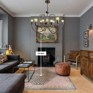 Brass candle-style Art Deco chandelier hanging in a living room with dark walls and vintage furniture