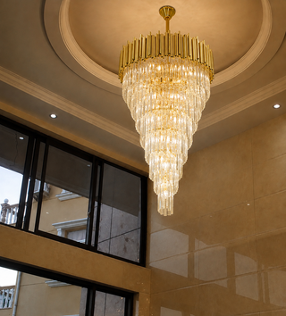 Large tiered crystal chandelier hanging in a two-story foyer with high ceilings