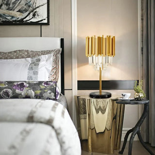 Gold crystal nightstand lamp glowing beside a bed