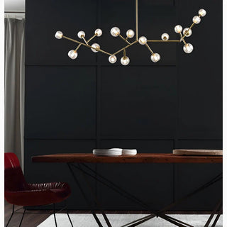 Copper molecular-shaped branching chandelier with small glass globes hanging above a wood dining table in a dark modern room