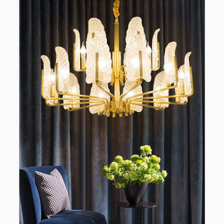 Lyss brass chandelier with frosted glass leaves hanging against a dark curtain
