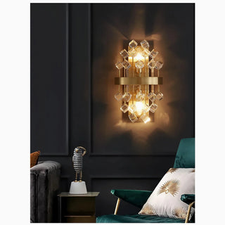 Rigaud crystal wall sconce lit against a dark wall beside a green armchair