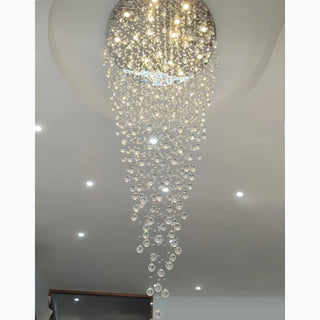 Large raindrop crystal chandelier with cascading crystal droplets in warm light above a living room