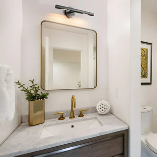 Modern LED vanity light above a bathroom mirror with marble countertop and brass faucet