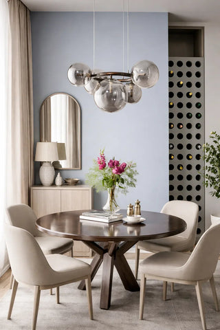 Cluster glass globe pendant chandelier hanging above a round wood dining table with upholstered chairs by Mirodemi