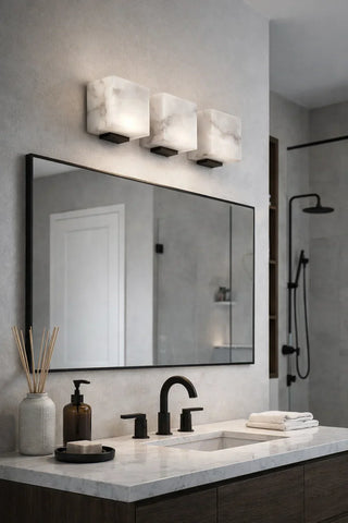 Marble bathroom vanity with a large mirror and wall sconces mounted above by Mirodemi