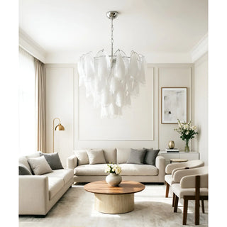 Modern living room with layered lighting: a sculptural chandelier, a floor lamp, and table lamps