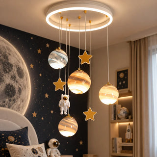 Astrielle Planet and Astronaut Chandelier hanging over a kid's bed with a space-themed mural