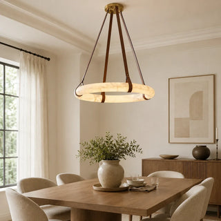Modern round LED chandelier hanging over a wooden dining table in a bright dining room