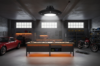 Black UFO-style high-bay LED light illuminating a workbench in a garage workshop