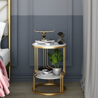 Small round gold and marble two-tier coffee table beside a bed