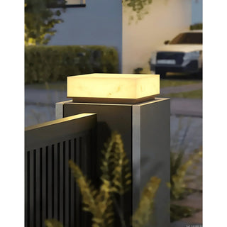 Illuminated pillar light capping a gate post at a driveway entrance