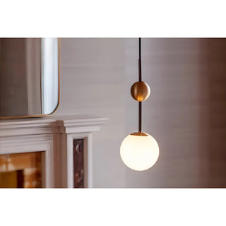 Clear glass globe pendant light hanging near a mirror and mantel