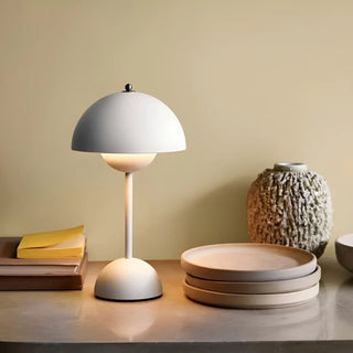 White mushroom-shaped table lamp glowing on a bedside console