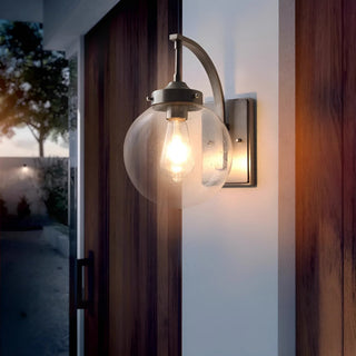 Coach light wall sconce mounted beside a front door on a covered porch