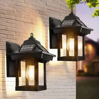 Solar-powered outdoor lantern sconces glowing on a brick wall at dusk