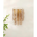 Close-up of amber glass wall sconce with soft glowing light, showcasing its detailed circular glass elements.