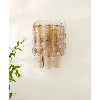Close-up of amber glass wall sconce with soft glowing light, showcasing its detailed circular glass elements.