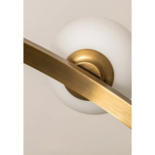 Close-up of a brass arm connecting to a white glass bulb in a modern chandelier design