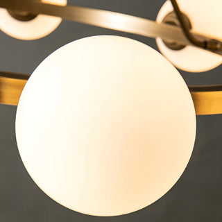 Detailed view of the milk glass sphere on the brass chandelier, highlighting its smooth, glowing appearance
