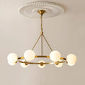 A brass chandelier with six white milk glass spheres, suspended from an elegant ceiling medallion