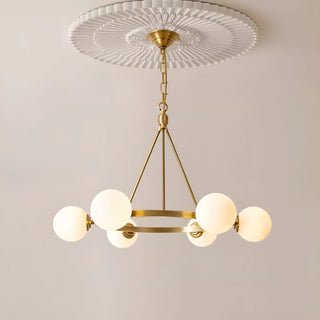 Close-up of a modern brass chandelier featuring sleek glass spheres, suspended from a decorative ceiling medallion