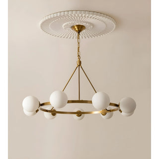 Full view of the brass chandelier with six white milk glass spheres, suspended from a classic ceiling medallion