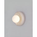Close-up view of an elegant natural stone wall sconce with a frosted glass globe, mounted on the wall in a modern living space