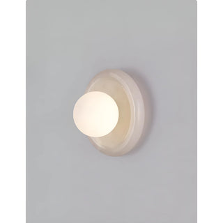 Close-up view of an elegant natural stone wall sconce with a frosted glass globe, mounted on the wall in a modern living space