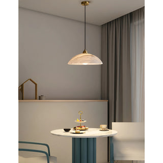 Lunara alabaster pendant light illuminating a cozy dining corner with brass accents and soft warm glow