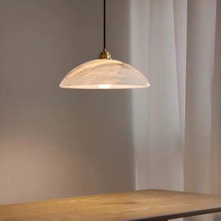 Lunara alabaster pendant light creating warm ambient lighting above a wooden table, perfect for kitchens or cafés