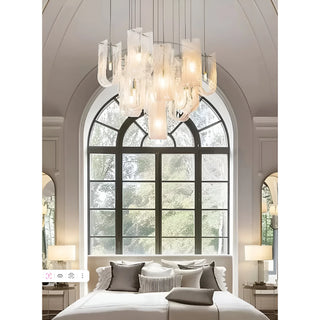 Contemporary chandelier with multiple frosted glass shades suspended from a round ceiling plate in a bright room