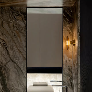 Amber glass disc wall sconce mounted beside bathroom mirror in modern marble interior