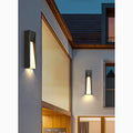 Sleek modern LED wall lights mounted on a house exterior, providing soft ambient lighting at dusk.