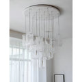 Contemporary chandelier with multiple frosted glass shades suspended from a round ceiling plate in a bright room