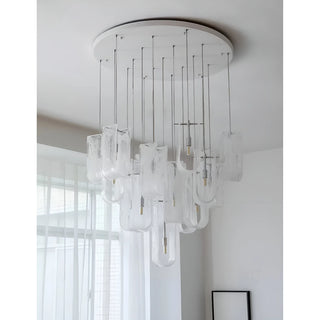 Contemporary chandelier with multiple frosted glass shades suspended from a round ceiling plate in a bright room