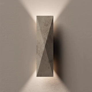 Close-up of the travertine stone wall light highlighting the geometric texture and warm illumination on a beige wall