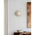 Soft lighting emitted from a natural stone wall sconce with a frosted glass globe, placed in a cozy room to create a warm atmosphere