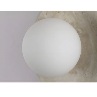 Close-up of a natural stone wall sconce with a white frosted glass globe, highlighting the sleek design and texture of the stone
