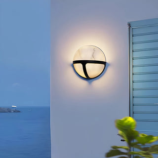 The Nube Marble Waterproof Outdoor Wall Light mounted on an exterior wall, casting a soft light at dusk in a modern setting