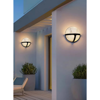 The Nube Marble Waterproof Outdoor Wall Light illuminating an exterior wall in the evening, adding a warm glow to the setting