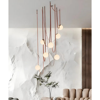 Scandinavian chandelier with leather straps and glass globes hanging in a modern living room interior with textured white wall