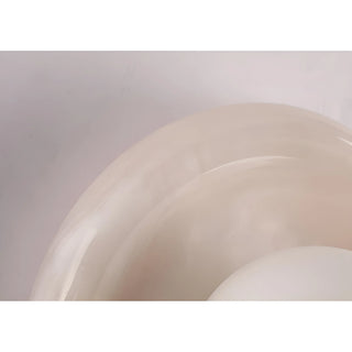 Detailed shot of a smooth, translucent stone wall light with a frosted glass globe, emphasizing the elegant curvature of the design