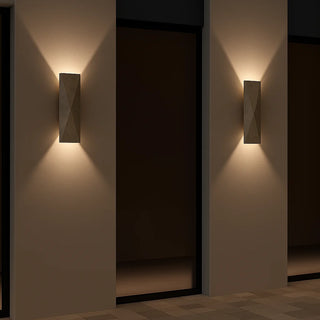 Еwo natural travertine wall lights on a modern minimalist exterior facade, emitting warm ambient light upward and downward