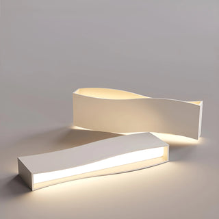 Two modern waveform LED light modules with curved surfaces emitting soft warm light on a neutral background