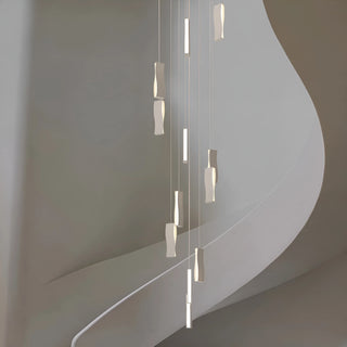 Modern waveform chandelier with sculptural LED pendants hanging along a minimalist staircase in a luxury home interior
