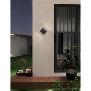 Aeris black LED wall sconce illuminating a modern outdoor patio at night