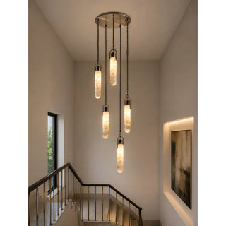 Luxury alabaster cluster staircase chandelier with five pendant lights installed in a modern stairwell with high ceilings.