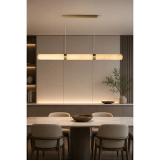 Alvara brass and alabaster linear pendant centered over a dining table in a warm modern interior